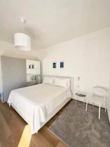 a white bedroom with a large bed and a chair at B&B Cellini in Santa Maria di Castellabate