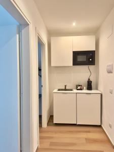 uma cozinha branca com um lavatório e um micro-ondas em B&B Cellini em Santa Maria di Castellabate