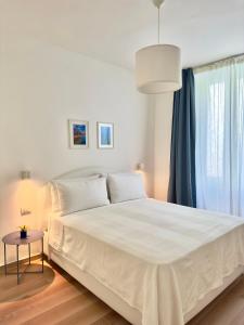 Cama blanca en habitación con ventana en B&B Cellini, en Santa Maria di Castellabate