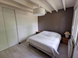 ein Schlafzimmer mit einem weißen Bett und einer Lampe in der Unterkunft Maison avec piscine 12m * 6m in Civrac-en-Médoc
