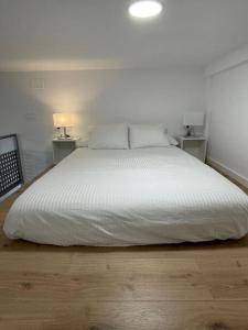 a bedroom with a large white bed with two lamps at MiniLoft #Baiona / in Baiona