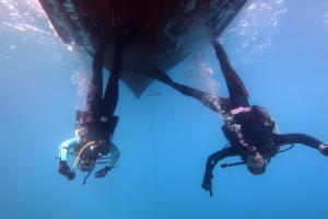 two people in the water next to a boat at Hobbit house Beli in Beli