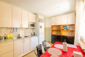 a kitchen with white cabinets and a red table and chairs at Cozy budget room w/ balcony in shared apartment in Vantaa