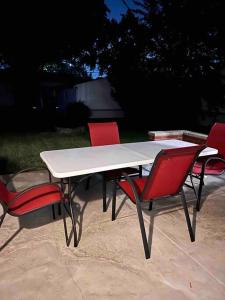 uma mesa branca com quatro cadeiras vermelhas à volta em Cozy Bungalow in Madison Heights em Madison Heights