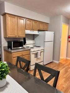 La cuisine est équipée d'un réfrigérateur blanc et de placards en bois. dans l'établissement Cozy Bungalow in Madison Heights, à Madison Heights