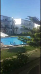 - une grande piscine avec des personnes dans l'établissement Bel Appartement pour vacances, à Sidi Rahal
