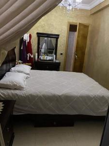 - une chambre avec un grand lit, une commode et un miroir dans l'établissement Bel Appartement pour vacances, à Sidi Rahal