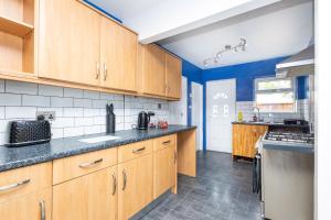 a kitchen with wooden cabinets and blue walls at Easterly Contractor Home - Free Parking, Self Check-in, Wi-Fi, Pool Table, Table Tennis, Air Hockey, Excellent Access to Leeds Centre in Roundhay