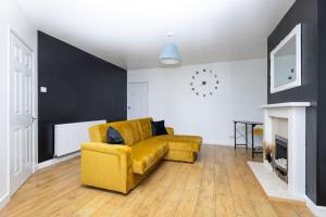a living room with a yellow couch and a fireplace at Easterly Contractor Home - Free Parking, Self Check-in, Wi-Fi, Pool Table, Table Tennis, Air Hockey, Excellent Access to Leeds Centre in Roundhay
