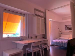 Cette chambre comprend une table, une fenêtre et un lit. dans l'établissement La casetta sul mare, à Anzio