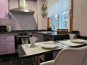 een keuken met paarse kasten en een tafel met stoelen bij Baiona-Mar, gastronomía y cultura in Baiona