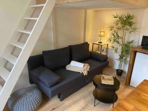 a living room with a black couch and a staircase at Charmant Studio in Vierzon
