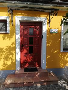 una puerta roja al lado de una casa amarilla en Apartment Antonia, en Dobova