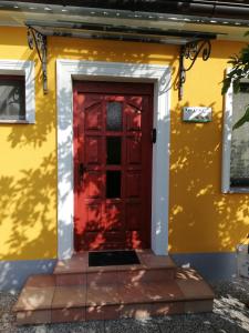 una porta rossa sul lato di una casa gialla di Apartment Antonia a Dobova