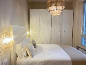um quarto com uma cama com lençóis brancos e almofadas em COQUETO APARTAMENTO em Torrelavega