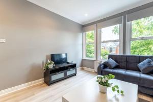 a living room with a couch and a tv at Cozy 3-Bedroom Flat in Willesden Green London in London