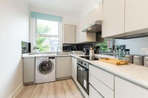 a white kitchen with a washing machine in it at Cozy 3-Bedroom Flat in Willesden Green London in London