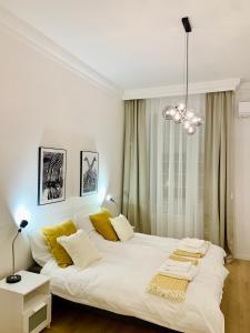 een slaapkamer met een groot wit bed met gele kussens bij MAIN SQUARE APARTMAN in Debrecen
