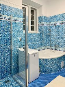 een blauw betegelde badkamer met een bad en een wastafel bij MAIN SQUARE APARTMAN in Debrecen