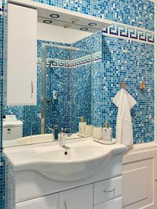 een badkamer met een witte wastafel en blauwe tegels bij MAIN SQUARE APARTMAN in Debrecen