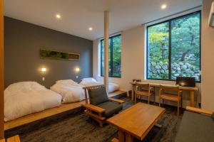 a bedroom with a bed and a desk and a table at Bessho Onsen Midoriya in Ueda