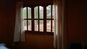 ventana en una habitación con cortinas y cama en Cabaña Aiken en Esquel