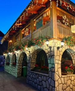 a building with a stone wall with flowers on it at Villa Miris Dunja in Zlatibor