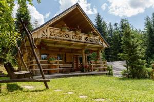 uma cabana de madeira com um alpendre e um banco na relva em Leśna Bacówka em Nowy Targ