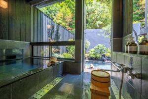baño con ventana grande con vistas a la piscina en Bessho Onsen Midoriya, en Ueda