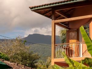 a building with a balcony with a mountain in the background at Pousada Atiaia in Ilhabela