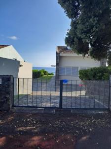 a fence in front of a house with the ocean in the background at Vivenda Moura, Caloura in Caloura