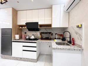 eine Küche mit weißen Schränken und einem Waschbecken in der Unterkunft Appartement VIP Panoramic Sea view et deluxe in Al Hoceïma