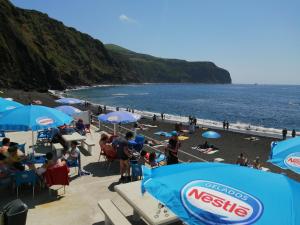 a group of people sitting on a beach with umbrellas at Casa Dos Mosteiros in Mosteiros