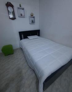 1 cama grande en un dormitorio con reloj en la pared en Apartamento Cómodo en Medellín, en Bello