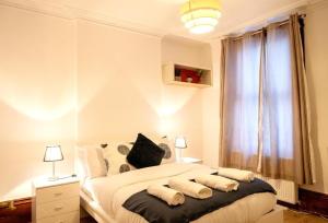sypialnia z łóżkiem z poduszkami i oknem w obiekcie Spacious 2 Bedroom Flat w Londynie