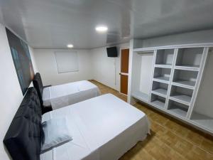 Una pequeña habitación con dos camas y un televisor. en Apartahotel Saroa, en Fonseca