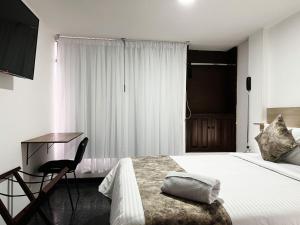 a bedroom with a bed and a desk and a chair at hotel versalles in Pasto