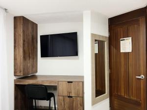 a room with a desk with a television and a chair at hotel versalles in Pasto