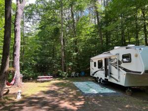 a white trailer parked in the woods next to a park at Lake Lauderdale Campground in Cambridge