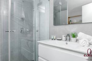 a white bathroom with a shower and a sink at דירה יוקרתית 100 מטר מהים - By Edomlux in Eilat +8 photos