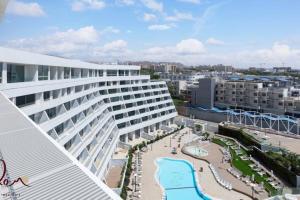 a large white building with a swimming pool next to a beach at Luxury living 100 meter from the beach - by Edom in Eilat