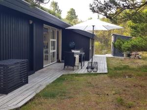 a patio with an umbrella and a table and chair at Holiday home Nørre Nebel LXXXIV in Nørre Nebel