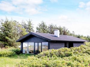 a black house with large windows in a field at Holiday home Bindslev XXII in Bindslev