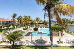 una piscina del complejo con sillas, sombrillas y palmeras en Condomínio Paradisíaco em Búzios, en Búzios