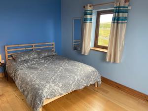 a blue bedroom with a bed and a window at Irish Isle Oasis: Spacious 5-Bedroom Retreat in Bungowla