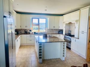 uma cozinha com armários brancos e uma grande ilha em Irish Isle Oasis: Spacious 5-Bedroom Retreat em Bungowla