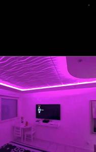 Habitación con luces rosas en el techo y TV. en Bron centre appartement meublé avec jacuzzi, en Bron