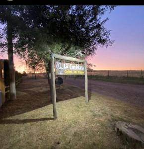 un cartel sentado en el césped junto a un camino en La Candelaria - Casas de Campo - en Sierra de la Ventana