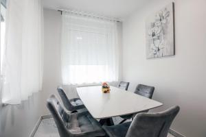a white dining room with a white table and chairs at Apartman STRONG in Slavonski Brod