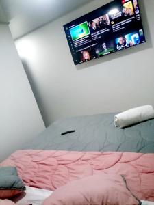 a bedroom with a bed with a tv on the wall at Casa Hospedaje - H in Bogotá
